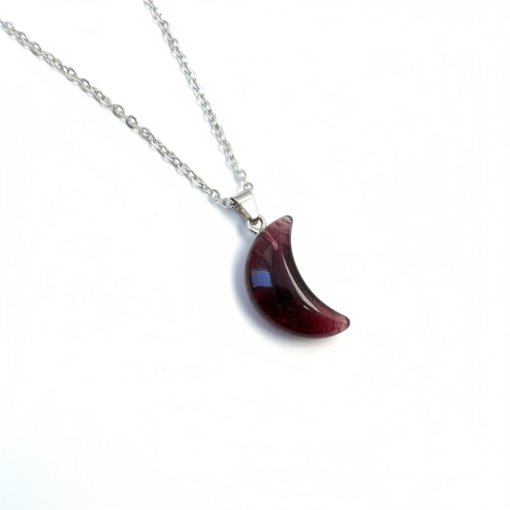 Garnet crescent moon necklace with dark red translucent stone pendant on silver chain, white background