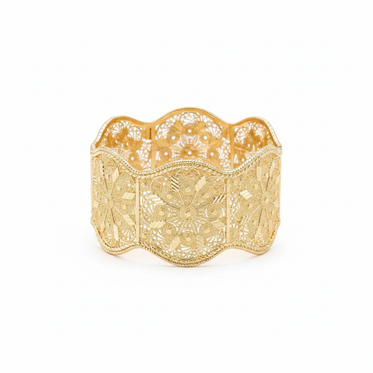 Gold filigree closed bangle bracelet on white background