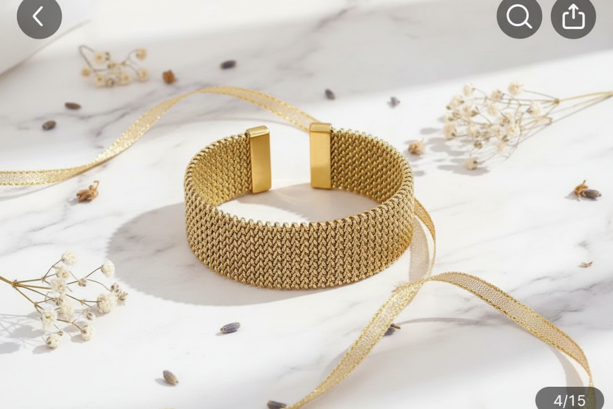 Wide gold mesh bracelet flat lay on white marble with gold ribbon and dried flowers